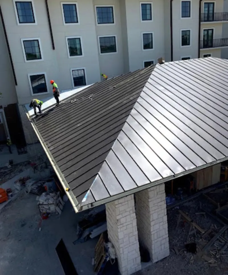 Crew installing standing seam metal roof panels on a commercial project in Maxatawny